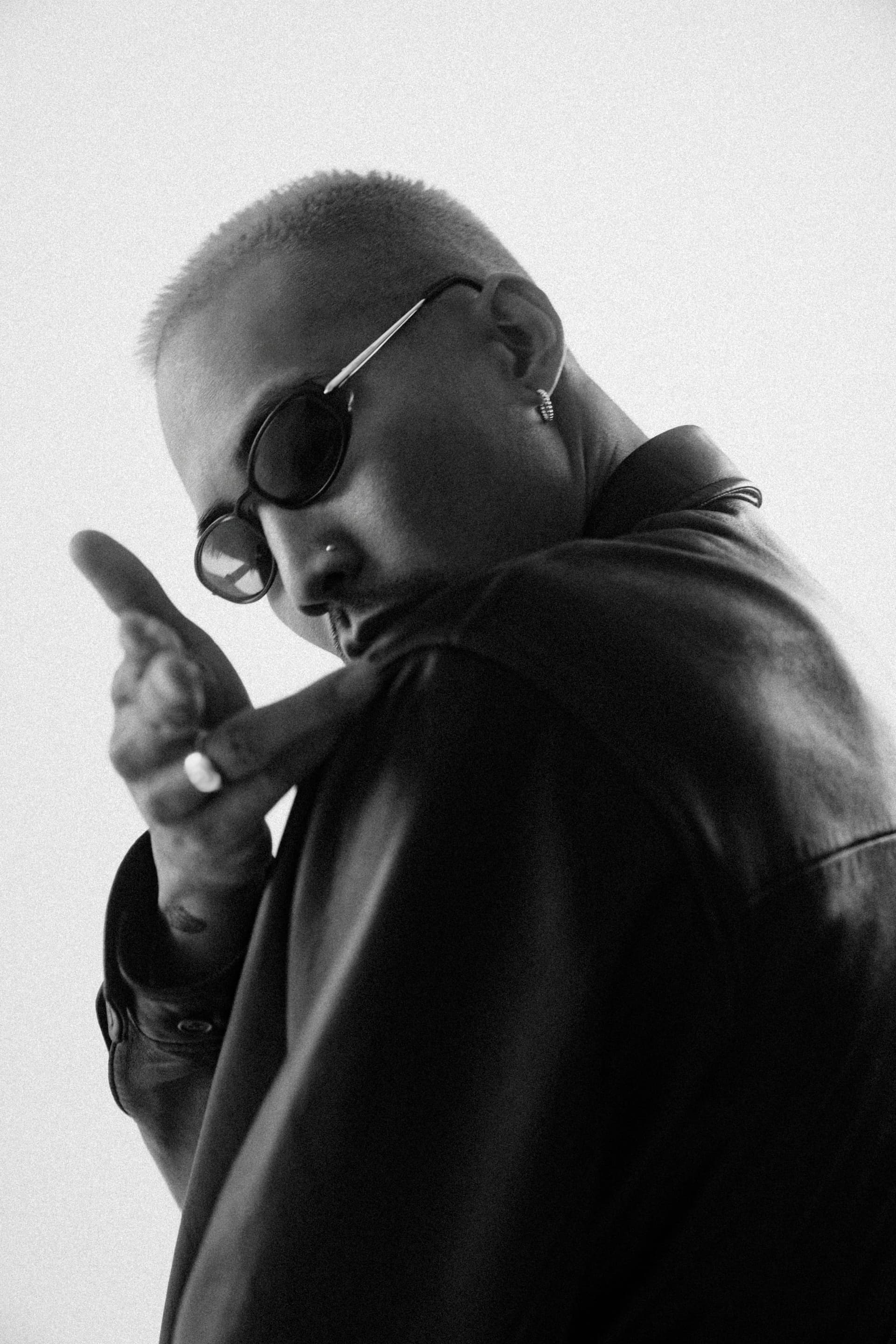 Person wearing sunglasses gesturing in natural lighting